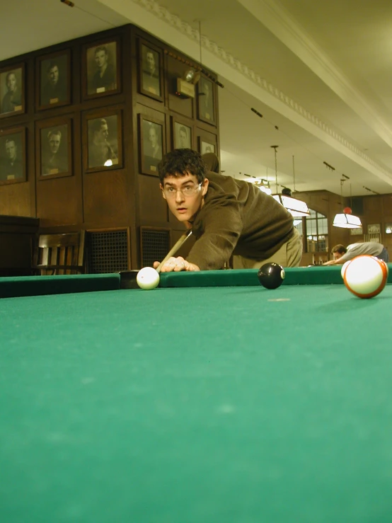 a man leaning over a pool table in an indoor area