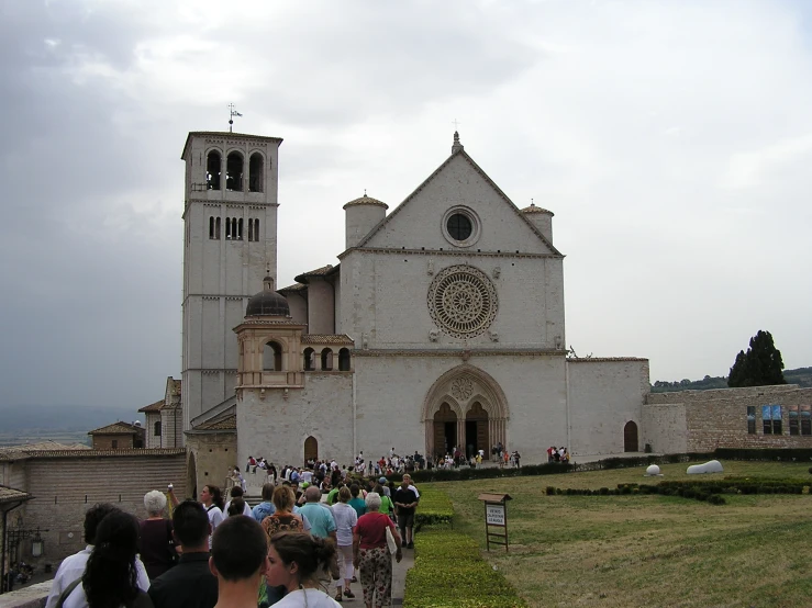 people walking towards an old white church