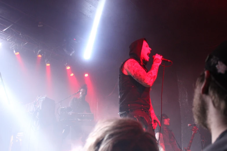 man singing into microphone with white lights above him