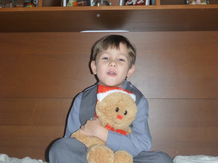 a little boy sitting in bed holding a teddy bear