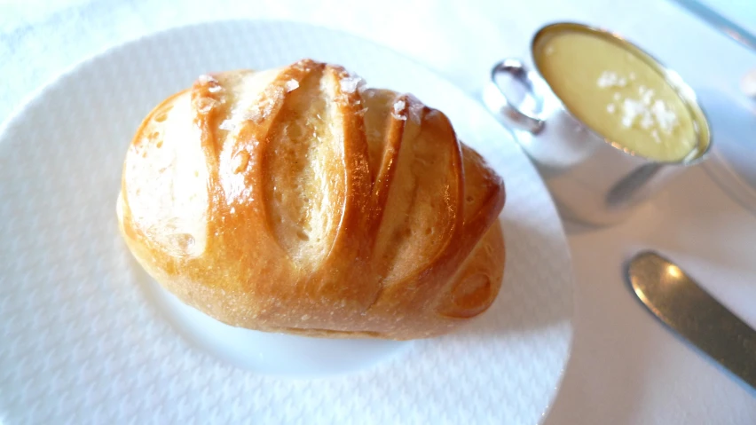 a croissant on a plate with a spoon on the side