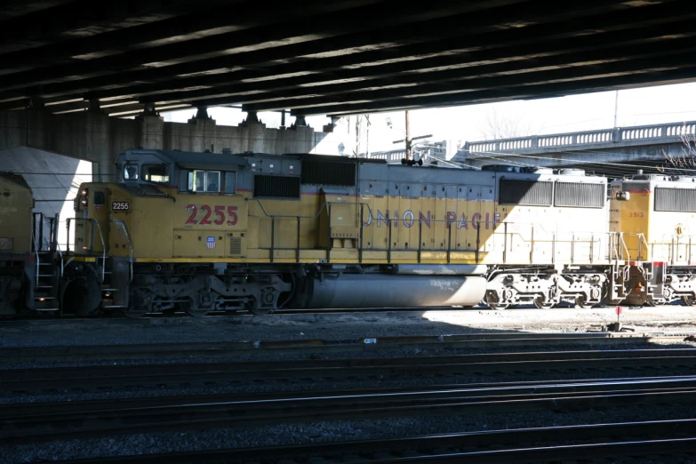 the yellow train is driving under a bridge