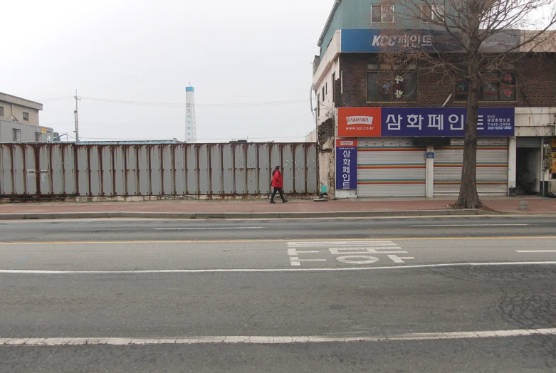 an empty street with a person walking on the sidewalk