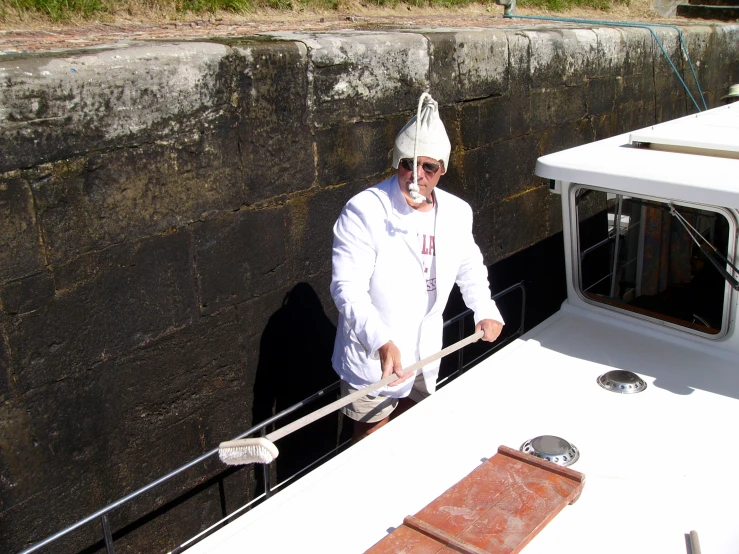 a man in a white suit cleaning the front of a boat