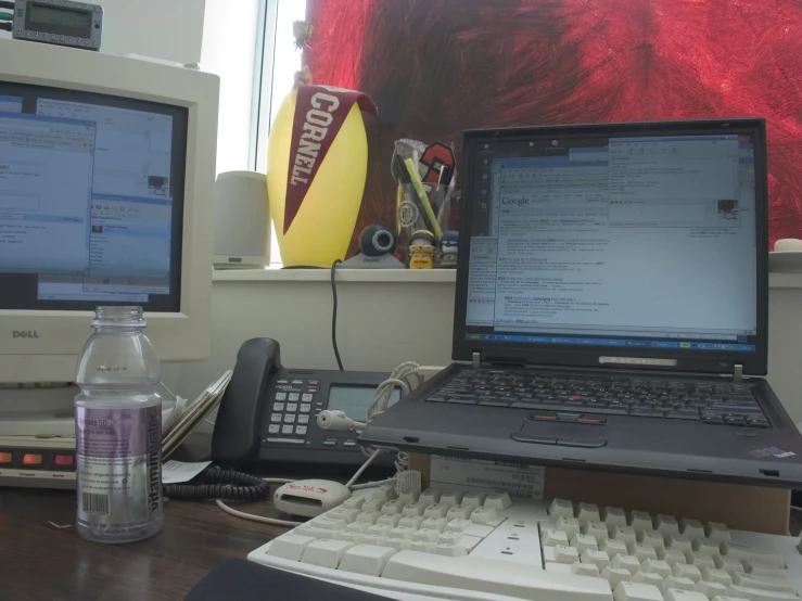 an office desk with a laptop, phone and other electronics