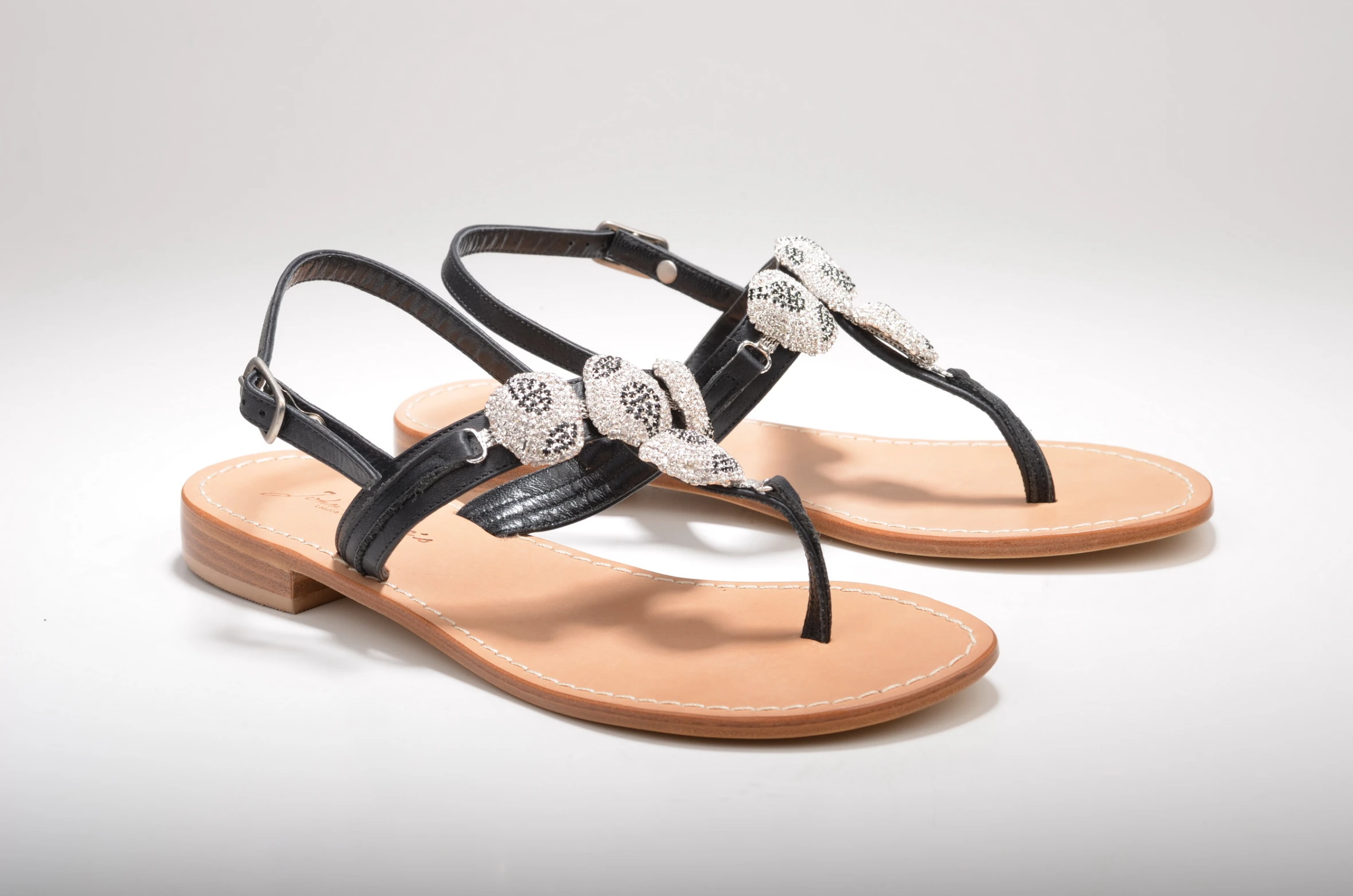 a womans black sandals with two flowered bows on them