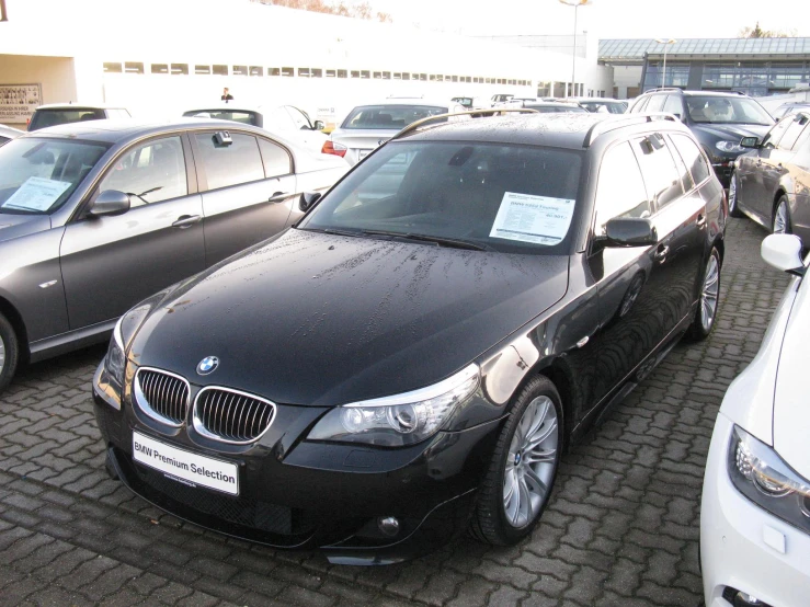 black bmw in lot near white toyota with prices on windshield