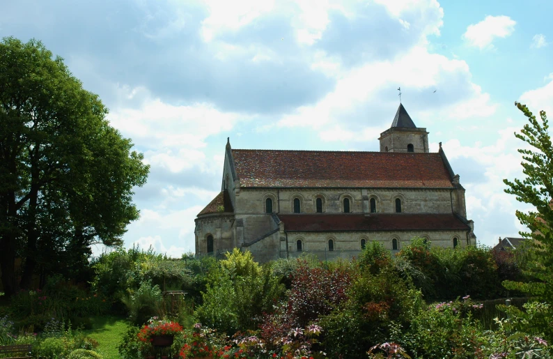 a large old church with flowers and trees