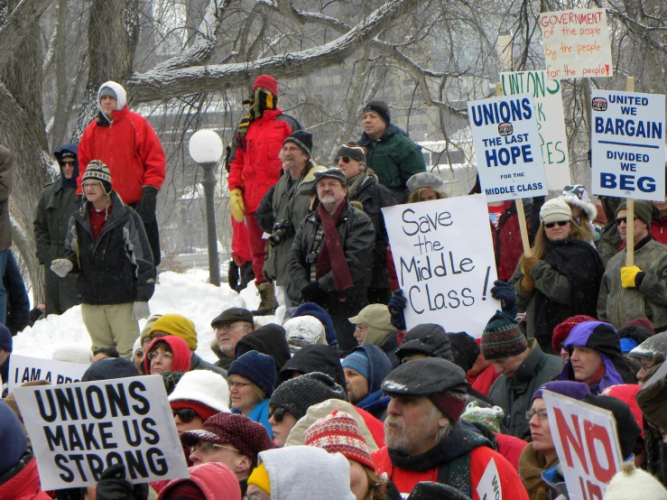 a group of people that are holding signs and standing in the snow