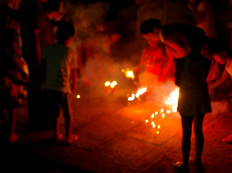 a crowd of people standing around a small fire pit