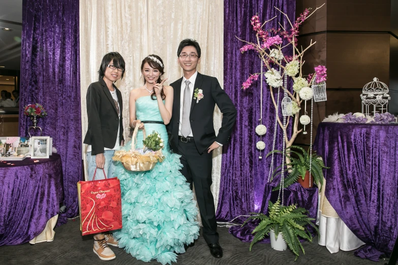 a couple and their two daughters standing in front of a table with purple curtains