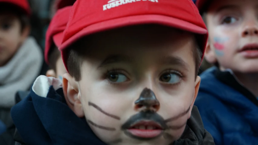 a child has painted on his face in front of two boys