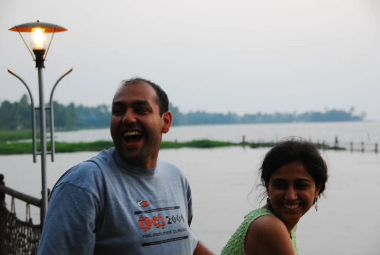 a man standing next to a woman and a lamp on top of a pier