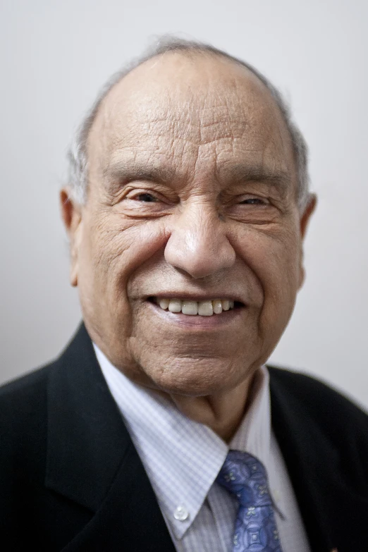 an older man is smiling while he wears a suit and blue tie