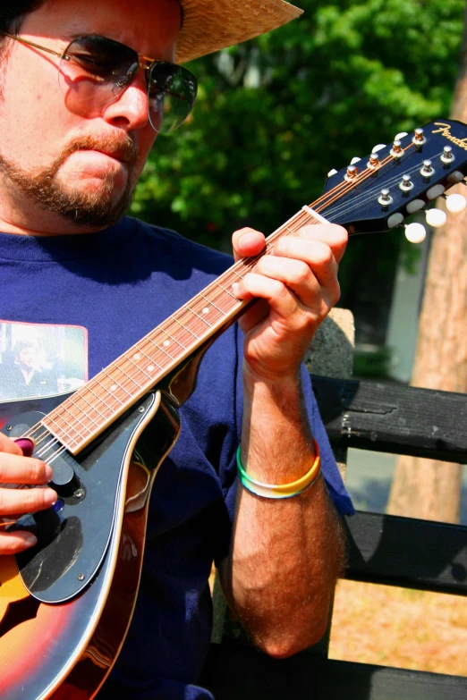 a man sitting down while playing guitar outside