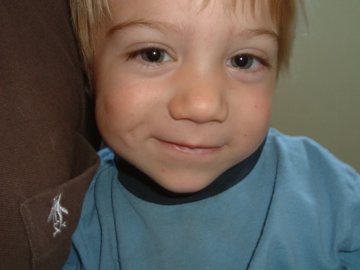 this is a small boy with light blonde hair and wearing a blue shirt