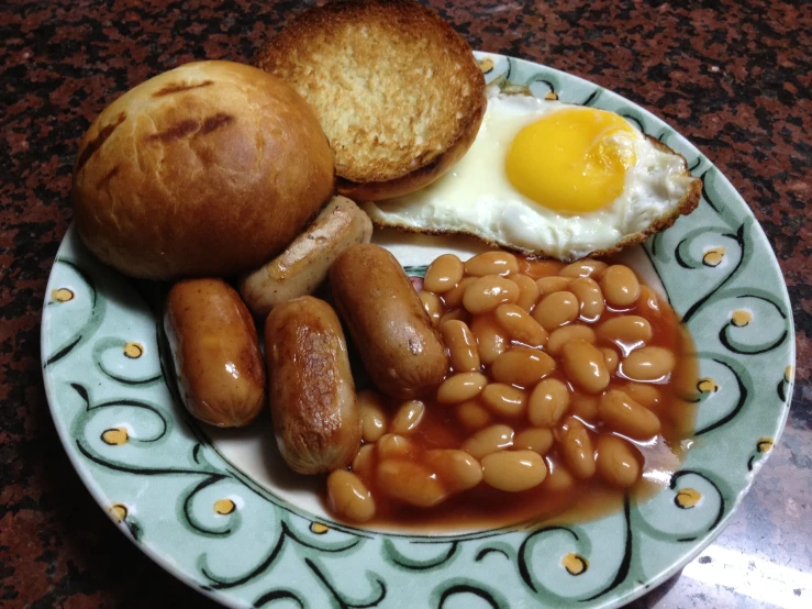 a meal is shown on a plate with eggs, beans and roll