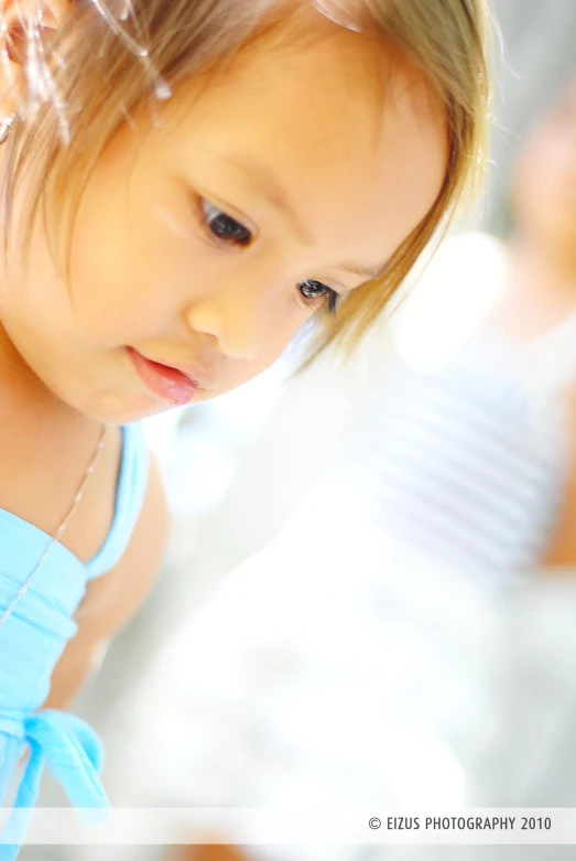 an adorable little asian girl in a blue dress looking down