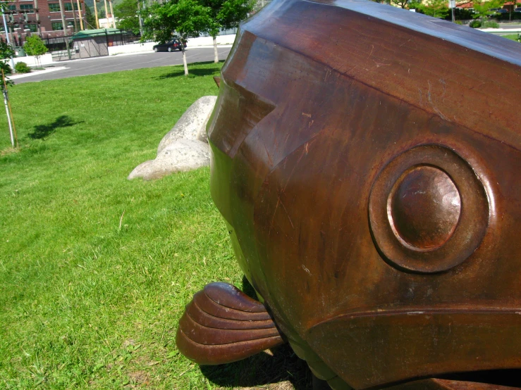 a big sculpture is in the grass by the road