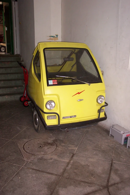 a small yellow car with the hood up