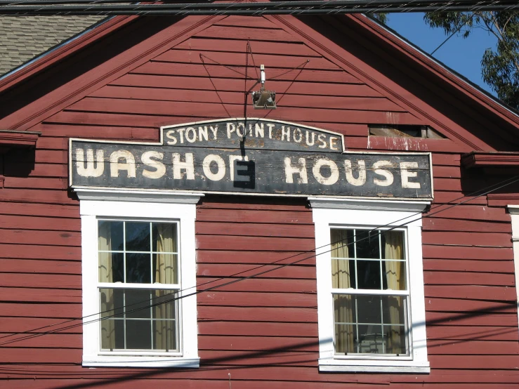the front of a red building with three white windows