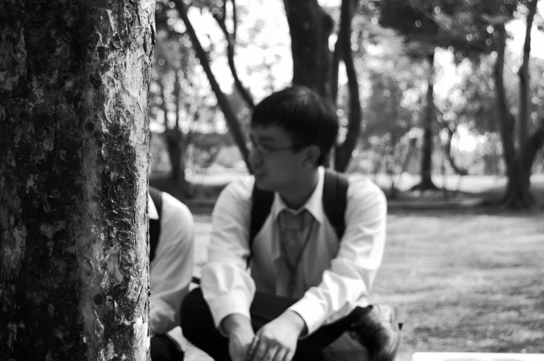 two young men sitting in the park one looking down