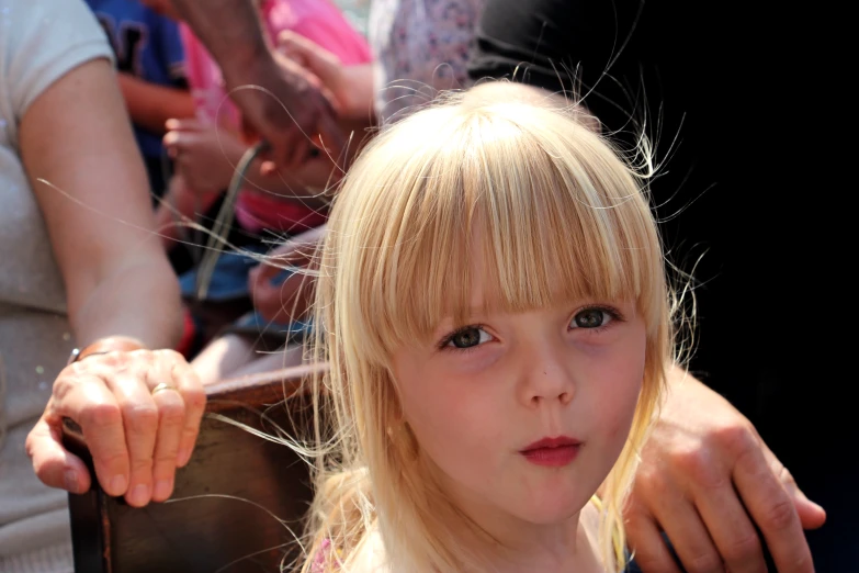 a little blond girl with light blue eyes staring into the camera