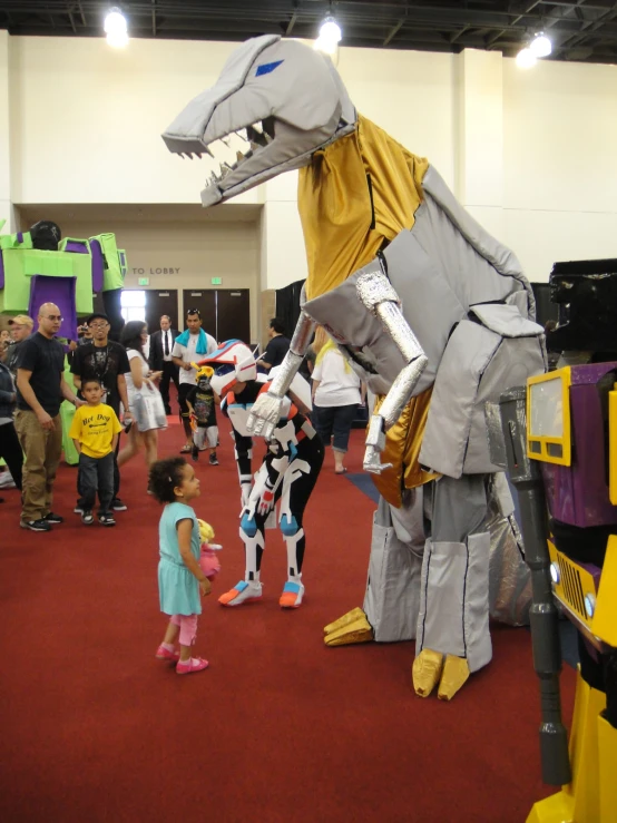 children are standing near large costumes that look like dinosaurs