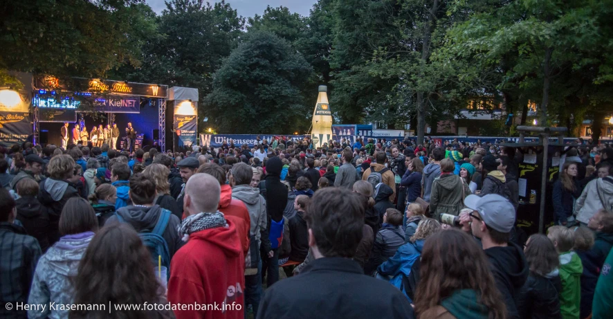 a large crowd of people outside by a stage