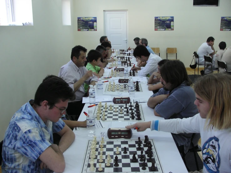 a group of people sitting around a table with chess pieces