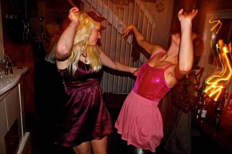 two women dancing in dresses at a party