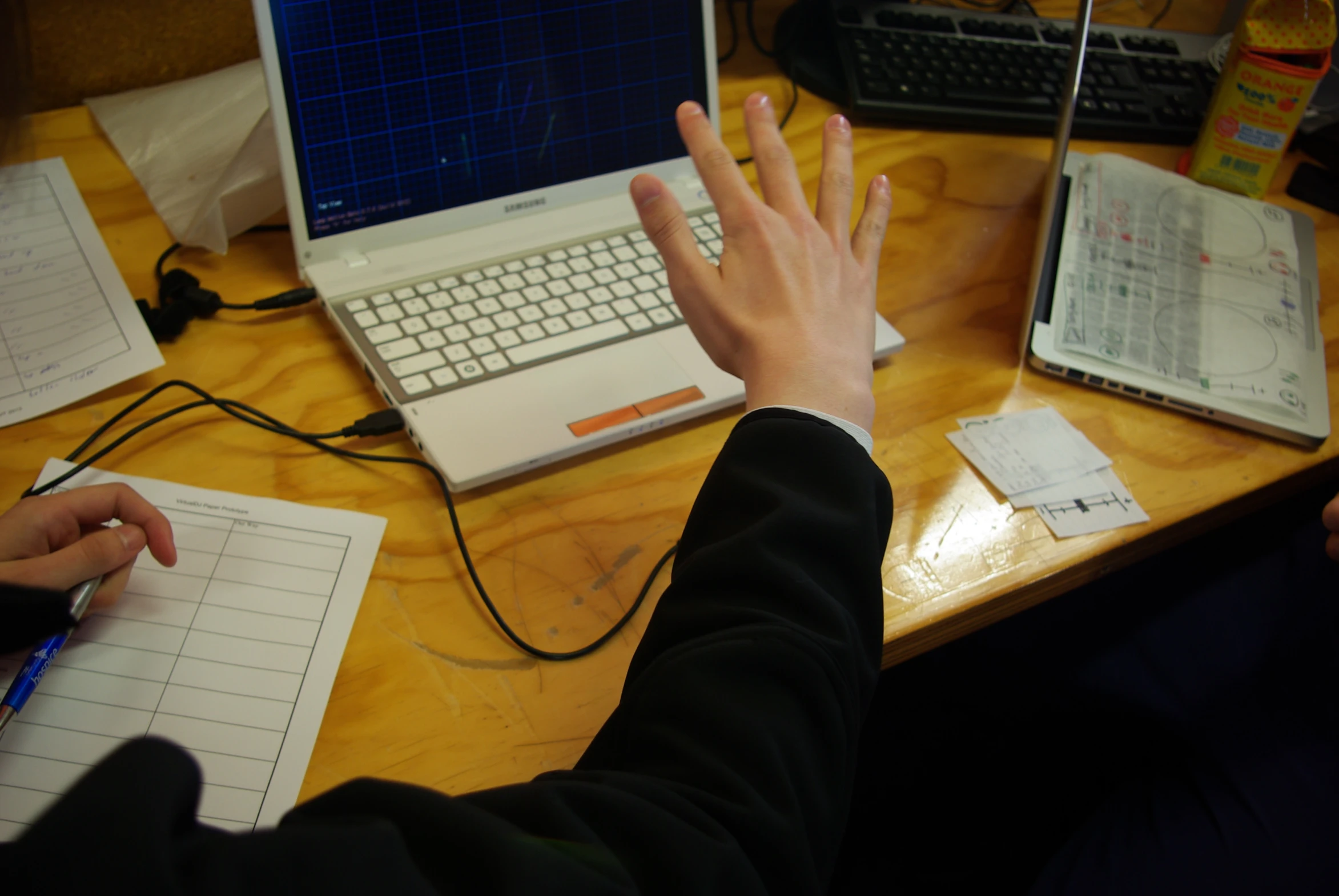 the person is sitting in front of the laptop on the table