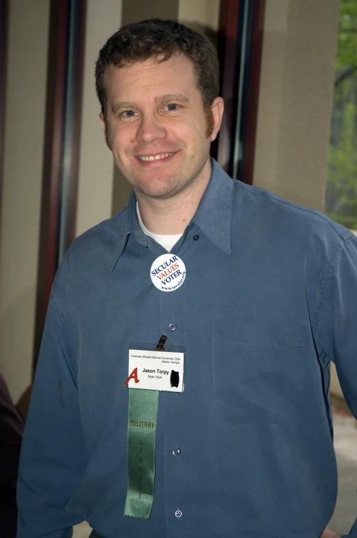 a man in a blue shirt with a small patch on his chest