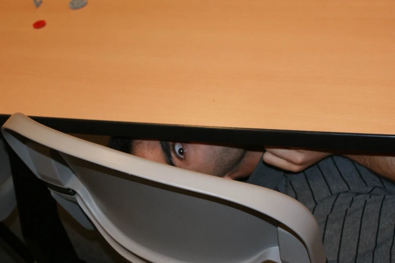 a man is peeking underneath a dining table