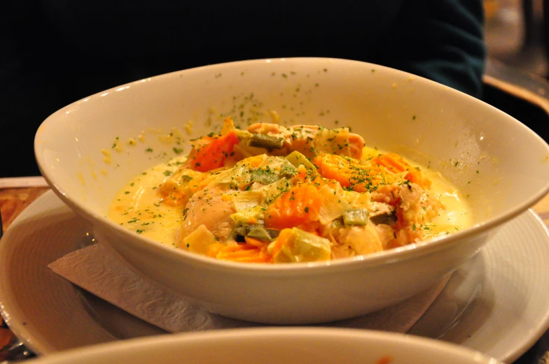 a bowl of vegetables on a plate with the serving utensils