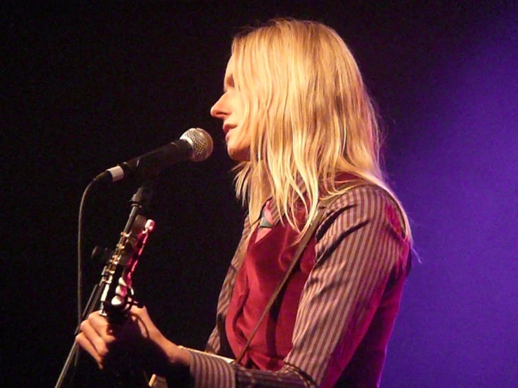 a blond female standing and holding a microphone