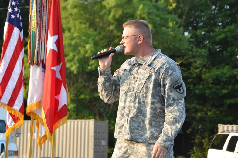 a man in uniform sings into a microphone