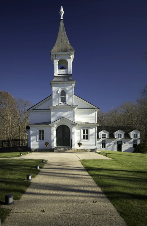 an old white church is standing in a grassy field