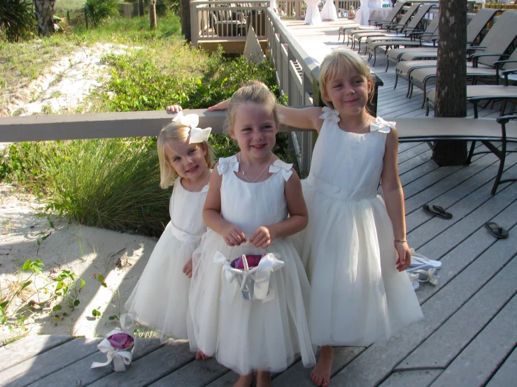 a group of children wearing flower dresses on a wooden deck