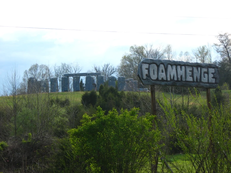 a road sign that says foamenge sitting in the middle of a lush green field