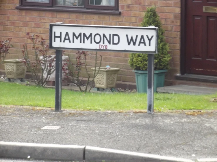 a black and white street sign is on the sidewalk