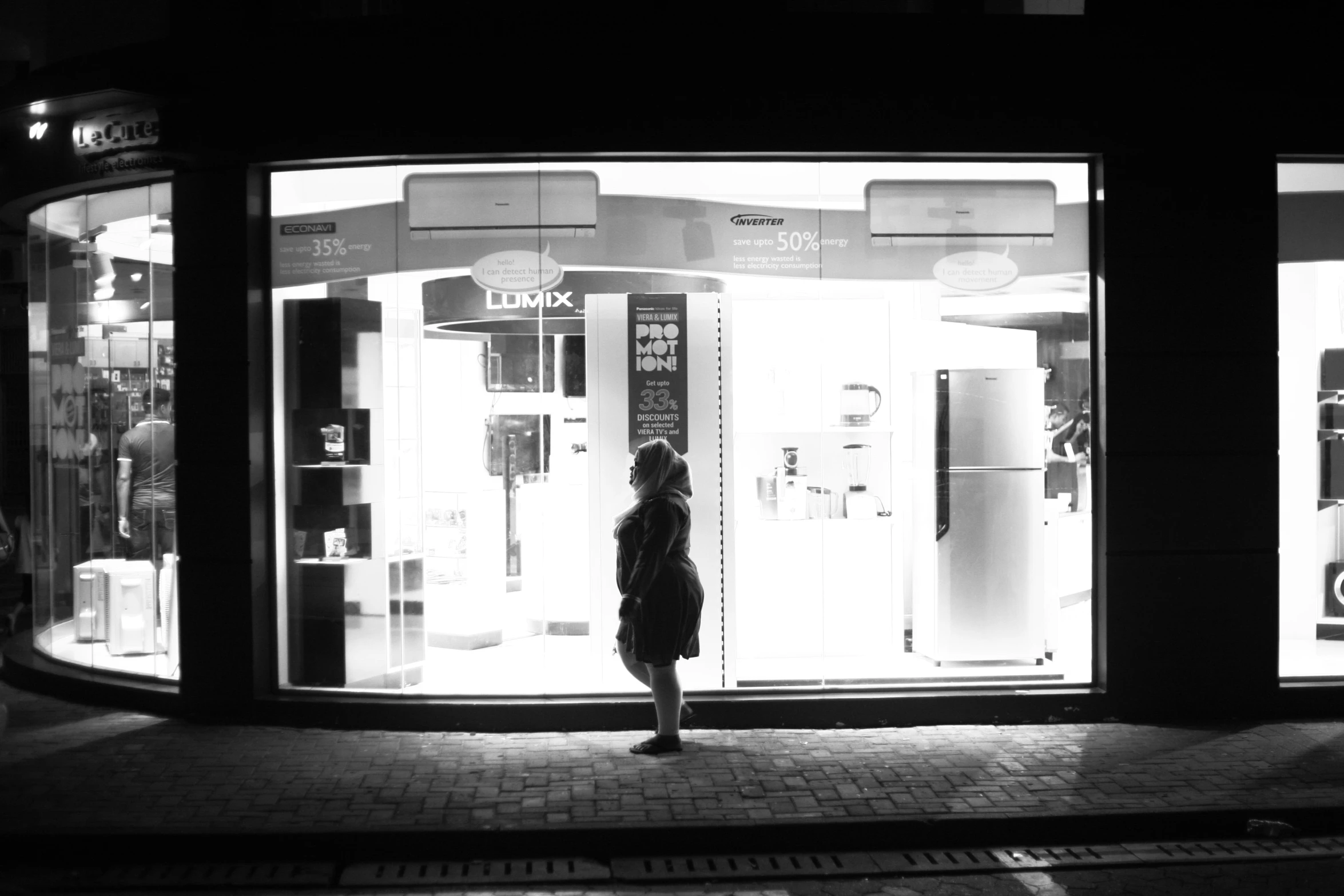 person standing outside of store front at night