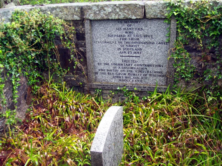 a tombstone surrounded by a stone wall with plants