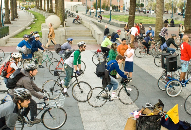 several bicyclists pass by on the sidewalk while people mill about