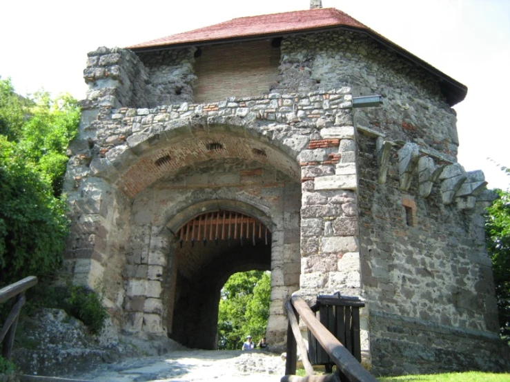 an old stone building sitting next to trees and a fence