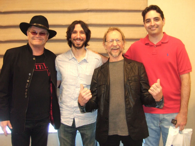 three men smile for the camera while holding their thumbs up