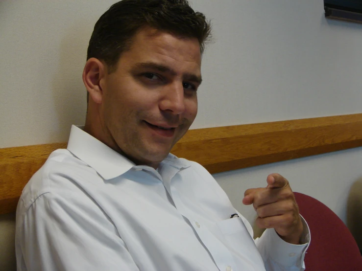 a young man wearing a dress shirt and pointing