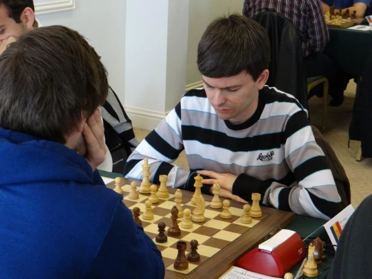 several men sit at a table playing chess