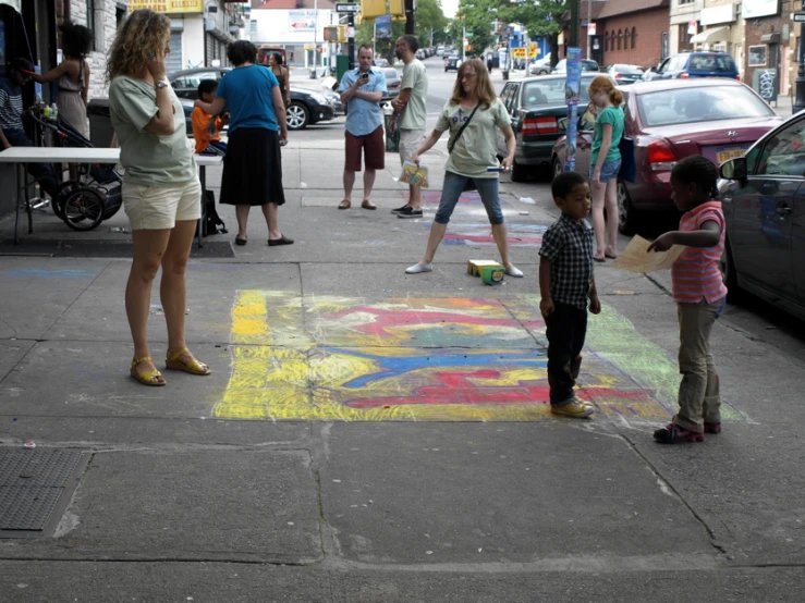 people are standing on the sidewalk, some are doing soing