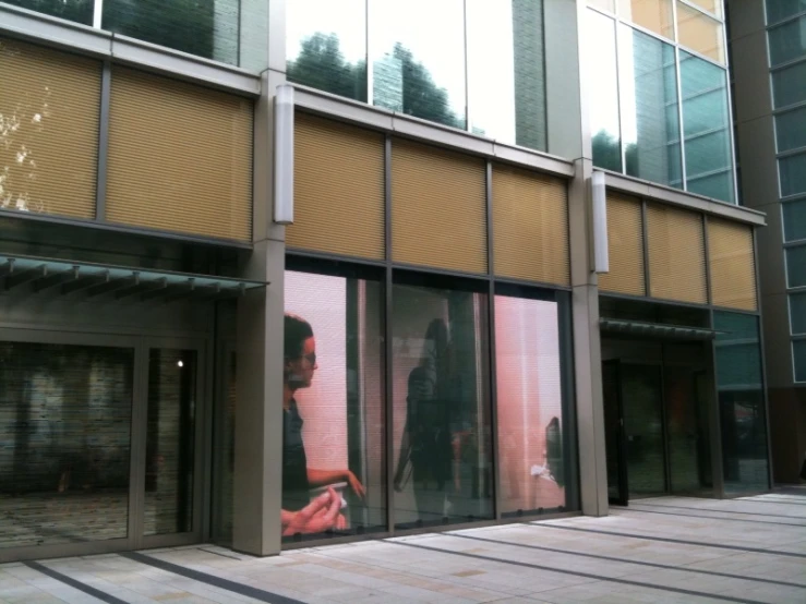 the back of a building with a man in the window using his phone